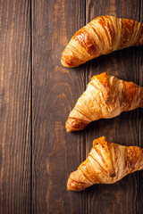 Food background with freshly baked sweet croissants on old wooden table. Breakfast or brunch concept with copy space, top view