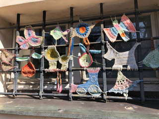 Cute macrame knitted figures made among the bars of a gothic window