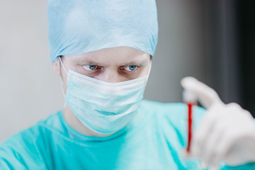 doctor in uniform examines a blood test in a medical test tube in a laboratory.