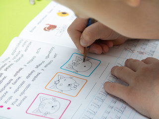 Moscow/Russia - 04.01.2020 : A boy does his homework. Distance learning in quarantine. Textbooks, notebooks are on the table. child's hand with a pencil