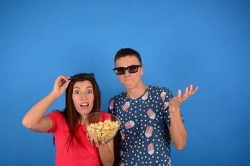 young couple in cinema with popcorn on a blue background