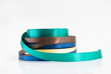 Stack of satin ribbon coils. Blue, green, brown and yellow ribbon for handmade. Needlework items.