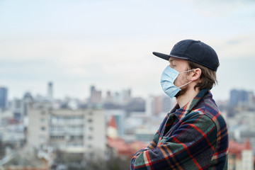 Young attractive man in a hat with medical face mask for mouth and nose covering. First protection...