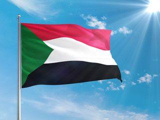 Sudan national flag waving in the wind against deep blue sky. High quality fabric. International relations concept.