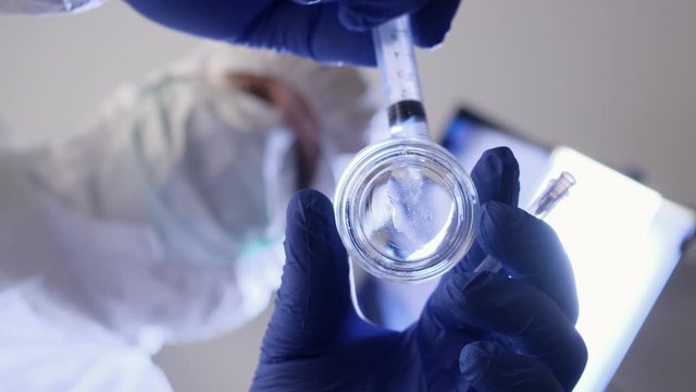 Laborant carefully preparing syringe for injection. Close up.