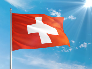 Switzerland national flag waving in the wind against deep blue sky. High quality fabric. International relations concept.