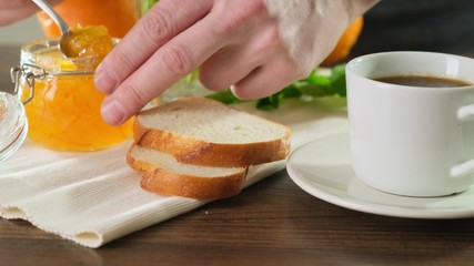 Tasty and hearty breakfast jam on crisp bread. Man makes a sandwich. Close up.