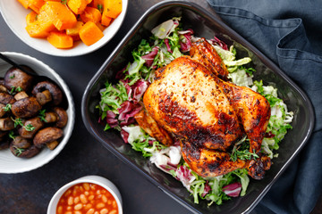 Table with whole roasted chicken, salad, pumpkin, mushrooms, beans