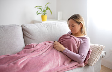 Girl with stomach ache sitting on sofa