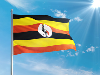 Uganda national flag waving in the wind against deep blue sky. High quality fabric. International relations concept.