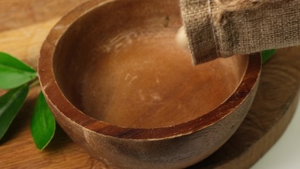 Slow motion dry cashew falling into wooden bowl on board. Close up.