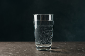 Glass with water on gray table, close up