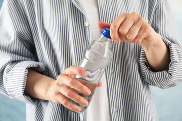 Person in shirt opens a bottle, close up