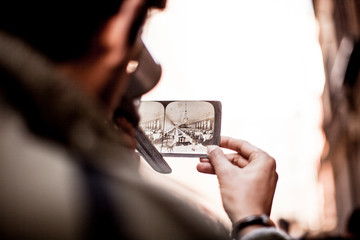 hombre observando fotografía 3D antigua por un estereoscopio