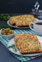 Homemade hot sandwiches with cheese and sausage in a plate, olives and cup of coffee on checkered tablecloth, Vertical format