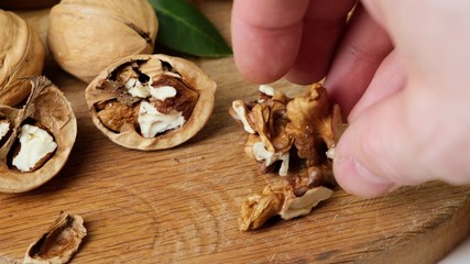 Female hands put peeled walnuts wooden board, close-up