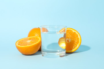 Orange and glass of water on blue background, close up