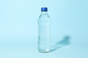 Bottle with water on blue background, space for text