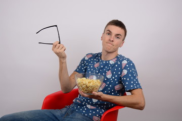 a man with popcorn sits on a chair in his hand 3D glasses of cinema