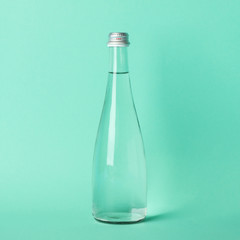 Bottle with water on mint background, space for text