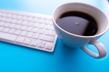 Creative flat lay photo of workspace desk. Top view office desk with keyboard and coffee cup on blue color background.