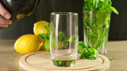 Pour cola in glass on wooden background. Close up.