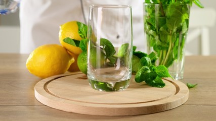 Pouring transparent soda water into a glass on wooden table. Close up.
