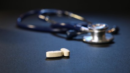 Hand man puts pills background of pills on table. Stethoscope on background. Close up.