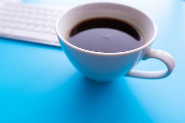 Creative flat lay photo of workspace desk. Top view office desk with keyboard and coffee cup on blue color background.
