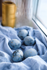 Blue Easter eggs are lying on the windowsill. Rustic style, natural materials and textiles, wooden walls.