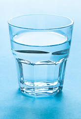 A transparent glass of water close up on the blue background. 