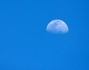 Partial moon as seen in the late afternoon in a tropical blue sky.