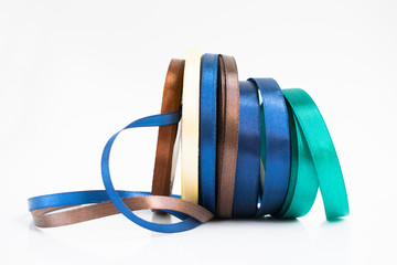 Stack of satin ribbon coils. Blue, green, brown and yellow ribbon for handmade. Needlework items.