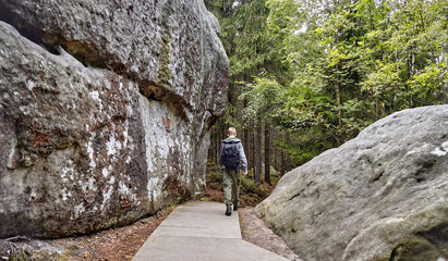 Rear view of a tourist visiting Errant Rocks (Błędne Skały)- rocks formed by erosion located in the Table Mountains National Park, Poland © PatPat