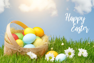 Basket with painted Easter eggs on green grass. Easter holiday concept.