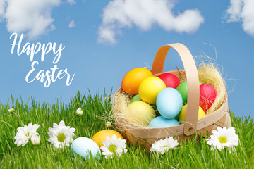 Basket with painted Easter eggs on green grass. Easter holiday concept.