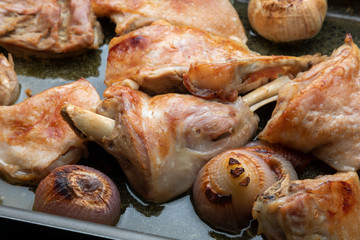 Roast meat of suckling lamb (suckling lamb). Fresh from the oven and smoking. Prepared on a roasting tray (with garlic and red onion).