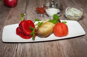 baked vegetables on a white plate with green branches on a wooden table