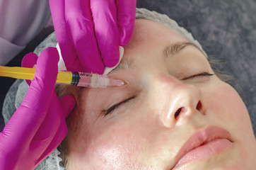 Woman face makes beauty injections around eyes, syringe