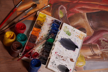 Master at work drawing made with gouache paints, still life. Paint cans and brushes hand of the master.