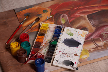 Master at work drawing made with gouache paints, still life. Paint cans and brushes hand of the master.