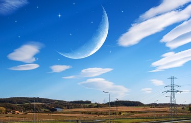 Moon in bright clouds of sunset sun . New moon , moon in the blue sky new moon in the clouds  © yaalan