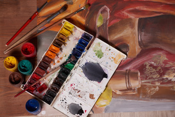 Master at work drawing made with gouache paints, still life. Paint cans and brushes hand of the master.