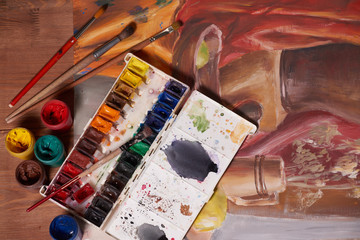 Master at work drawing made with gouache paints, still life. Paint cans and brushes hand of the master.