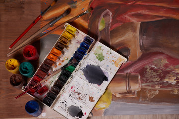 Master at work drawing made with gouache paints, still life. Paint cans and brushes hand of the master.