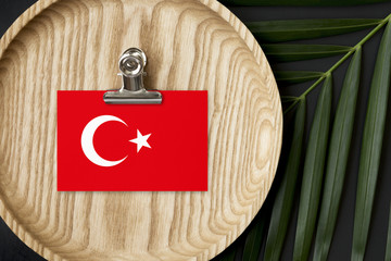 Turkey flag tagged on wooden plate. Tropical palm leaves monstera on background. Minimal national...