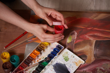 Master at work drawing made with gouache paints, still life. Paint cans and brushes hand of the master.