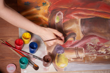 Master at work drawing made with gouache paints, still life. Paint cans and brushes hand of the...
