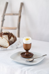 broken boiled egg on a wooden stand on a table with a white tablecloth