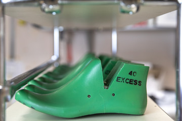Green shoe lasts in a row on shelf in foot wear factory